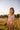 Girl wearing ARNICA CRUDO - ALANA LONGSLEEVE swimsuit in a sunny field, showcasing floral pattern and UV protection.