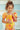 Girl wearing VERANERA AMARILLO - BUBBLE ONE PIECE swimsuit, sipping a fresh drink in a colorful setting.