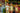 Three kids in vibrant banana-print swimwear standing in a fruit market surrounded by fresh produce.