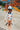 POLILLA ARCOIRIS CRUDO long sleeve swimsuit worn by a smiling girl at a water park.