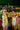 Two girls wearing Banano Colombiano Bamba One Piece swimwear with banana print and puffy straps, smiling at a market.